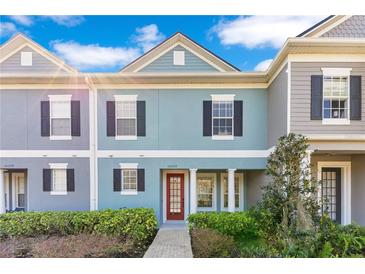 Charming two-story townhome featuring a red door and neatly landscaped front yard at 10226 Vickers Ridge Dr, Orlando, FL 32829