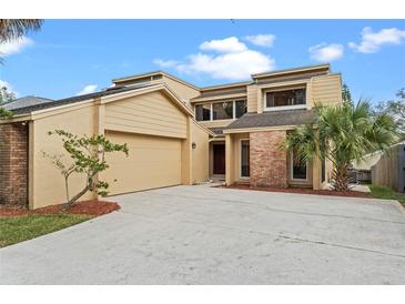 Inviting tan two-story home with attached garage, mature landscaping, and brick accents at 229 Springside Rd, Longwood, FL 32779