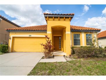 Charming yellow home featuring a tile roof, well-manicured lawn, and a welcoming front porch at 2610 Rosemont Cir, Davenport, FL 33837