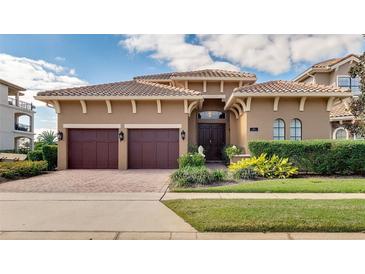 Elegant home featuring a tile roof, symmetrical landscaping, and a two-car garage on a sunny day at 314 Muirfield Loop, Reunion, FL 34747