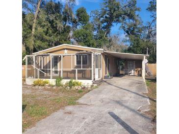 Charming single-story home featuring a screened porch and covered carport with a paved driveway at 31700 Orange St, Sorrento, FL 32776