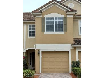 Two-story townhome featuring a tan exterior, private garage, and well-maintained landscaping at 3401 Shallot Dr # 107, Orlando, FL 32835