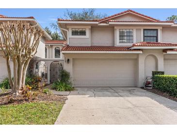 Charming townhome featuring a two-car garage, landscaped yard, and a gated front entryway at 7709 Sundial Ln, Orlando, FL 32819