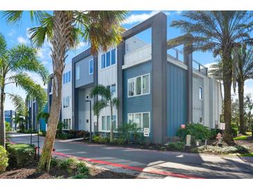 Modern townhome exterior with blue and gray siding, palm trees, and well-maintained landscaping at 7770 Sandy Ridge Dr # 212 Bldg 27, Kissimmee, FL 34747