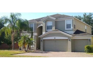 Charming two-story home with three-car garage, manicured lawn, and mature palm trees at 854 Lost Grove Cir, Winter Garden, FL 34787