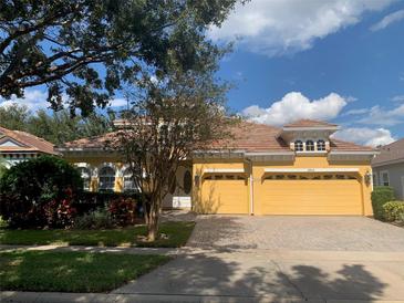 Charming one-story home featuring a two-car garage, lush landscaping, and a stylish clay tile roof at 8908 Via Bella Notte, Orlando, FL 32836