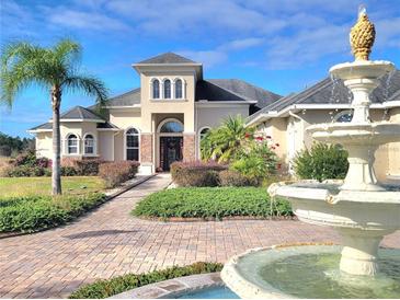 Stunning two-story home featuring manicured landscaping and elegant fountain in the front yard at 12625 Sweet Hill Rd, Polk City, FL 33868