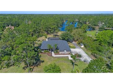 Beautiful aerial view of a brick home featuring a lush, treed landscape and a tranquil lake backdrop at 1303 Sultan Cir, Chuluota, FL 32766