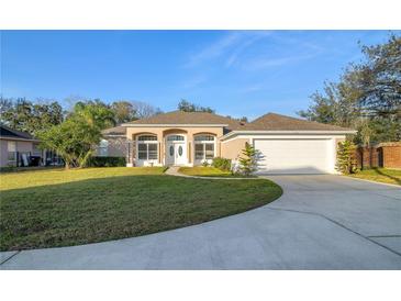 Charming single-story home featuring an arched entryway, well-manicured lawn and attached two-car garage at 13330 Meergate Cir, Orlando, FL 32837