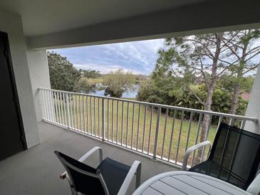 Balcony view overlooking the green lawn and lake with outdoor seating available at 13941 Fairway Island Dr # 733, Orlando, FL 32837