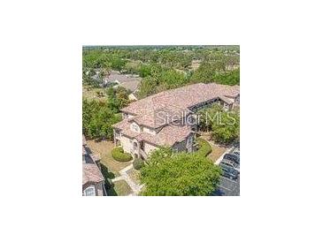 Aerial view of the condominium complex featuring a terracotta roof and ample parking at 13941 Fairway Island Dr # 733, Orlando, FL 32837