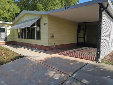 Charming single-story home with a covered carport and an expansive concrete driveway at 1765 W Schwartz Blvd, Lady Lake, FL 32159