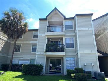 Three-story condo featuring balconies, sliding glass door, and mature palm tree at 1932 Lake Atriums Cir # 77, Orlando, FL 32839