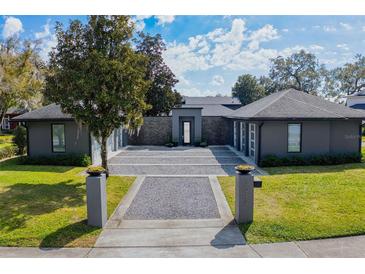 Contemporary home featuring a sleek gray exterior, stone accents, and a beautifully landscaped front yard at 2010 Hoffner Ave, Belle Isle, FL 32809