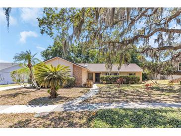 Exterior of a well-maintained tan home with mature trees and shrubs in the landscaped front yard at 3547 Medford Rd, Casselberry, FL 32707