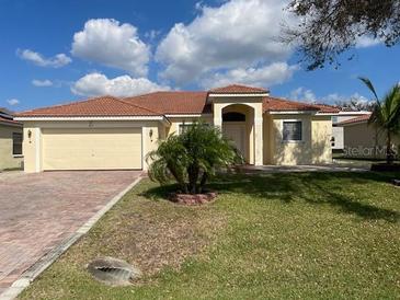 Inviting single-story home with a red-tile roof, a two-car garage, and manicured landscaping at 415 Cinnamon Dr, Kissimmee, FL 34759