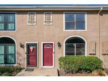 Charming townhome featuring red doors, neutral stucco, and large windows at 606 Casa Park I Court, Winter Springs, FL 32708