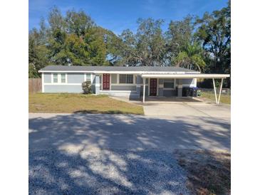 Charming single-story home with a carport, red doors, and lush trees at 723 Jeffcoat St, Apopka, FL 32703