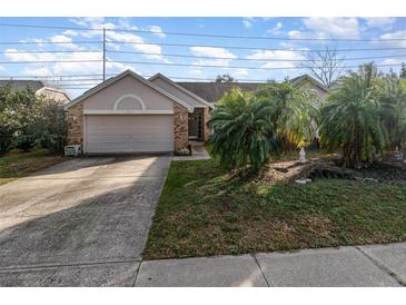 Charming single-story home featuring a two-car garage and mature palm trees in the front yard at 12972 Broakfield Cir, Orlando, FL 32837