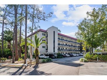 Exterior shot of a multi-story condo with a red roof and ample parking at 200 El Camino Dr # 402, Winter Haven, FL 33884