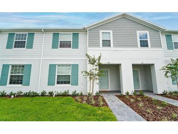 Charming townhome featuring a well-manicured lawn, beautiful walkway, and a freshly painted facade at 207 Jetty Way, Davenport, FL 33897