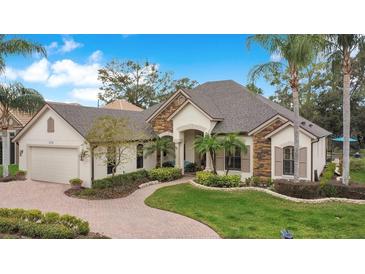 Beautiful single-story home features manicured lawn, stone accents, and brick-paved walkway to the entry at 210 Laurel Park Ct, Winter Park, FL 32792