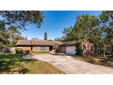 Charming single-story home featuring a brick facade, a wide driveway, and mature landscaping at 4124 Winderlakes Dr, Orlando, FL 32835