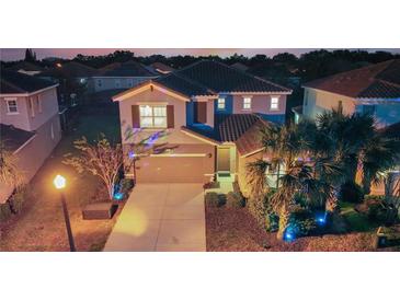 Charming two-story home featuring a well-manicured lawn, tile roof, and two car garage in the evening at 5234 Wildwood Way, Davenport, FL 33837