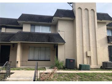 Two-story townhome featuring neutral paint, dark roof, and an exterior A/C unit at 5415 Fairwood Way # 303, Orlando, FL 32808