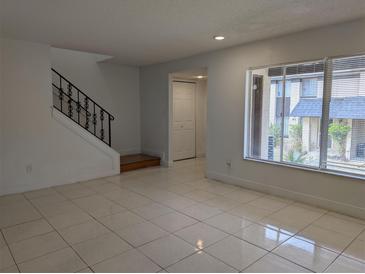 Bright living room with tile flooring, staircase, and natural light from a window at 5415 Fairwood Way # 303, Orlando, FL 32808