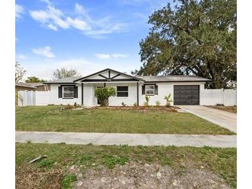 Charming single-story home with white facade, black trim, attached garage, and well-maintained front lawn at 7331 Blue Jacket W Pl, Winter Park, FL 32792