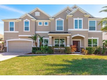 Stately home with a manicured lawn, brick-paved driveway, attached two-car garage, and neatly trimmed landscaping at 15165 Heron Hideaway Cir, Winter Garden, FL 34787