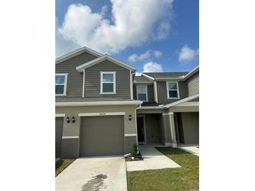 Two-story townhome featuring a two-car garage and neutral-tone horizontal siding at 9436 Westside Hills Dr, Davenport, FL 33896