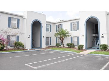 Condo exterior showcasing the building's white facade, blue shutters, arched entrances and parking area at 1006 Plantation Dr # F11, Kissimmee, FL 34741