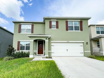 Charming two-story home featuring a well-manicured lawn and attached two-car garage at 2029 Maple Ridge Dr, Zellwood, FL 32798