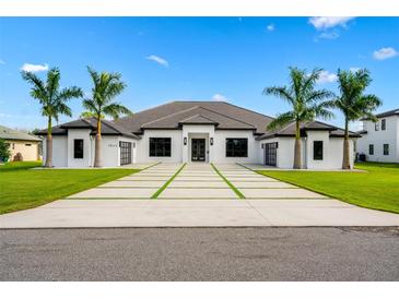 Stunning white modern home featuring a tile roof, decorative driveway, and lush landscaping with palm trees at 3845 S Stillwood Ln, Lake Mary, FL 32746