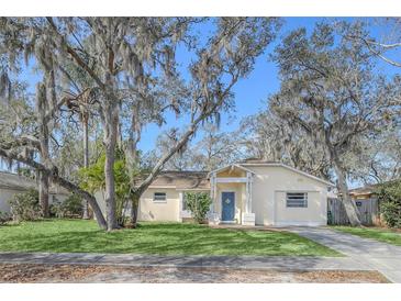 Charming home featuring a well-manicured lawn, mature trees, and welcoming blue front door at 388 Winnway St, Apopka, FL 32712