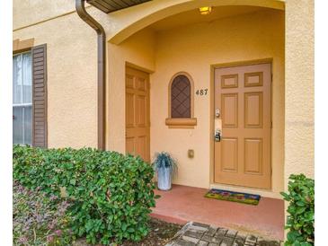 Charming condo entrance featuring well-manicured landscaping and a welcoming, covered doorway with the address 487 at 487 La Mirage St, Davenport, FL 33897