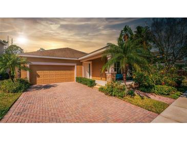 Charming single-story home featuring a brick driveway, attached garage, and well-maintained tropical landscaping at 7736 Brofield Ave, Windermere, FL 34786