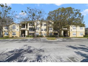 Exterior of a light yellow two-story apartment building complex on a sunny day with reserved parking spaces at 2624 Robert Trent Jones Dr # 634, Orlando, FL 32835