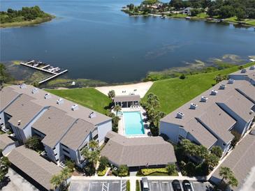 Aerial view of a waterfront community with a swimming pool, sandy beach, and boat docks on a sunny day at 4117 Fairview Vista Pt # 105, Orlando, FL 32804