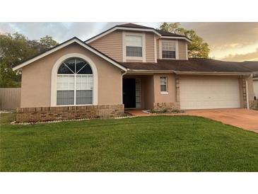 Charming two-story home features a manicured lawn, attached garage, and a welcoming facade with large windows at 7138 Hiawassee Bent Cir, Orlando, FL 32818