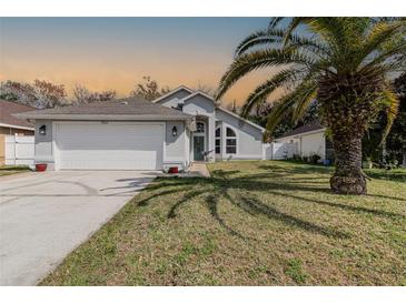 Charming single-story home featuring a well-maintained lawn, attached garage, and a beautiful palm tree in the front yard at 8982 Fort Jefferson Blvd, Orlando, FL 32822