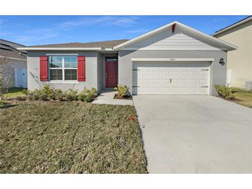 Charming one-story home featuring a two car garage, red shutters, and a red front door at 1925 Arbor Mill Ln, Kissimmee, FL 34744