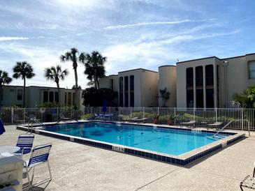 Community pool with ample seating surrounded by lush, tropical landscaping on a sunny day at 516 Orange Dr # 17, Altamonte Springs, FL 32701