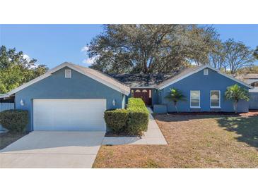 Charming blue home featuring an attached two-car garage, manicured bushes, and a lovely front entrance at 1320 Corte Nueva, Winter Springs, FL 32708