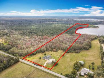 Expansive aerial view of a large lot home with a backdrop of lush trees and a lake at 1680 Blackwelder Rd, De Leon Springs, FL 32130