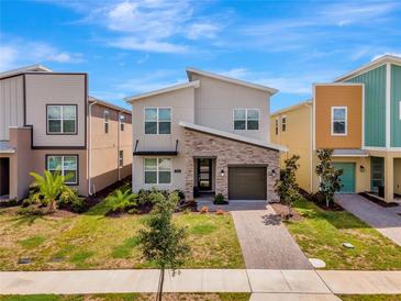 Modern two-story home with stone accents, manicured lawn and blue sky at 4164 Paragraph Dr, Kissimmee, FL 34746