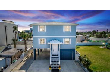 Charming elevated beach house with blue siding, white trim, and well-manicured lawn at dusk at 435 Jessamine Ave, New Smyrna Beach, FL 32169