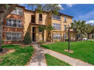 Well-maintained condo building with lush landscaping, sidewalk, and palm trees on a sunny day at 5120 Conroy Rd # 513, Orlando, FL 32811
